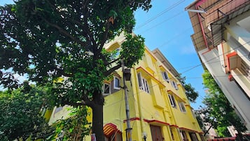 Un edificio de varios pisos con fachada amarilla, múltiples ventanas y un balcón visible.