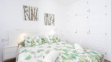Une chambre à coucher avec un lit, deux tableaux accrochés au mur, une armoire et une table de chevet.
