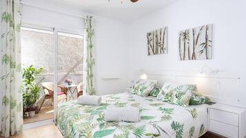 Ein Schlafzimmer mit einem Bett, einem Nachttisch, einem Deckenventilator und Blick ins Freie.