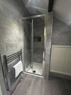 Une salle de bain moderne avec une douche à parois de verre, un meuble blanc et un porte-serviettes.