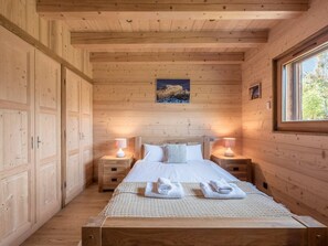 A wooden cabin bedroom with a bed, nightstands, and a window. - Chalet 10 people : incredible view and fireplace (Les Houches)