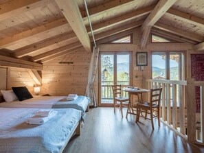 A wooden cabin with a loft bedroom, a dining area, and a balcony with a view. - Chalet 10 people : incredible view and fireplace (Les Houches)