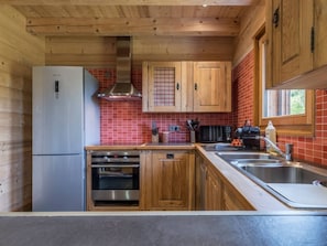A kitchen with wooden cabinets, a stainless steel refrigerator, a built-in oven, and a red-tiled backsplash. - Chalet 10 people : incredible view and fireplace (Les Houches)