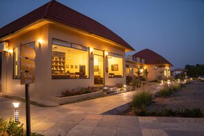 A two-story building with a red-tiled roof, a reception desk, and a bar area visible through the windows. - Jawai Zinc Journey By The Fern, Jawai (Pali)