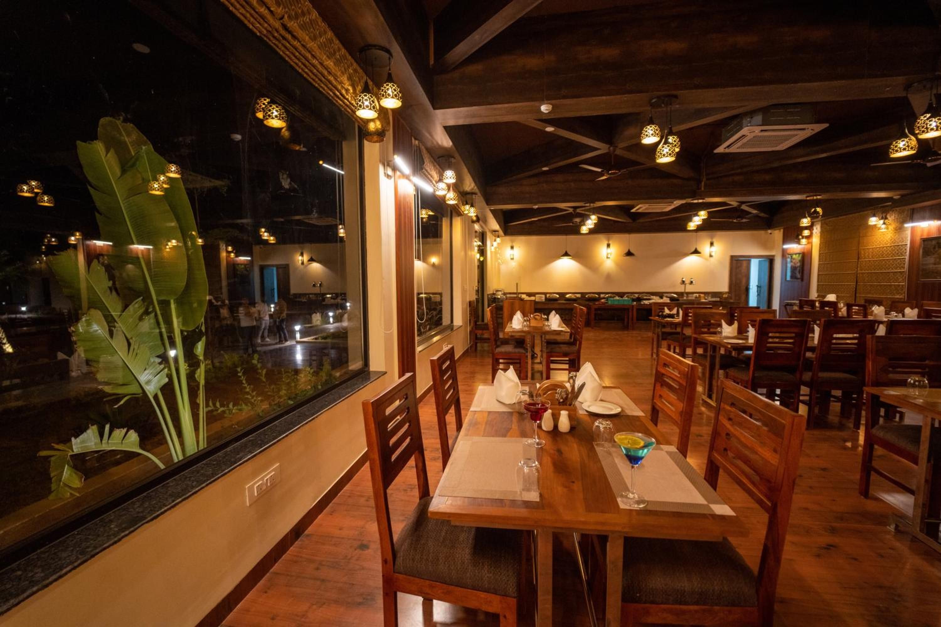 A restaurant with wooden furniture, a large window with a view, and pendant lighting.