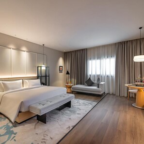 A modern hotel room with a large bed, a seating area, and a dining table. - Braira Jazan Hotel (Jizan)