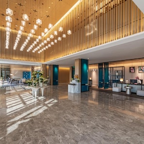 A spacious lobby with a high ceiling, modern lighting fixtures, and a reception desk. - Braira Jazan Hotel (Jizan)