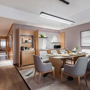 A modern kitchen with a dining area, featuring a long table set for six, wooden cabinetry, and a marble backsplash. - Braira Jazan Hotel (Jizan)