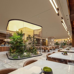 A modern restaurant with a glass enclosure containing tropical plants, marble tables, and chairs. - Atour Hotel Shenzhen CBD Futian Metro Station (Shenzhen)