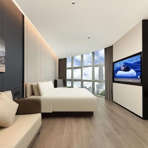 A modern hotel room with a large bed, a sofa, a TV on the wall, and a city view through the windows. - Atour Hotel Shenzhen CBD Futian Metro Station (Shenzhen)