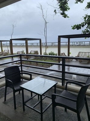 An outdoor seating area with tables and chairs, overlooking a body of water.