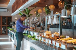 A buffet setup with various food items and a person serving.