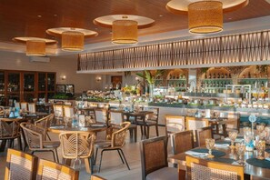 A restaurant with round tables, wicker chairs, and hanging lamps. - The Tropics at Macarthur Park (Palo)