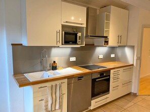 A modern kitchen with white cabinetry, a stainless steel sink, a microwave, an oven, and a dishwasher. - Alpenblick.Hoch3 Vacation rental with two separate bedrooms and three balconies facing east-southwest (Aschau im Chiemgau)