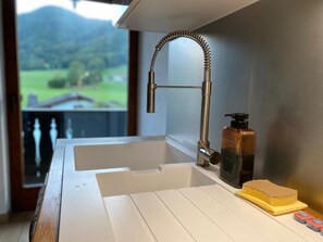 A kitchen with a stainless steel sink, a soap dispenser, and a sponge on the counter. - Alpenblick.Hoch3 Vacation Rental with two separate bedrooms and three balconies facing east-south-west (Aschau im Chiemgau)