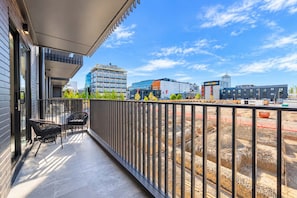 Ein Balkon mit Blick auf eine Baustelle und moderne Gebäude im Hintergrund.
