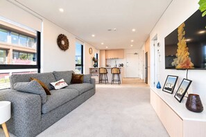 Ein modernes Wohnzimmer mit einem grauen Sofa, einem Couchtisch und einem an der Wand montierten Fernseher.