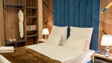 Ein Hotelzimmer mit Bett, Nachttischen, einem Kleiderschrank und einem blauen Kopfteil.