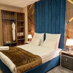 A hotel room with a bed, bedside tables, a wardrobe, and a blue headboard. - Piano Suites (Baku)