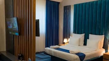 A hotel room with a bed, a TV, a coffee maker, and a nightstand.