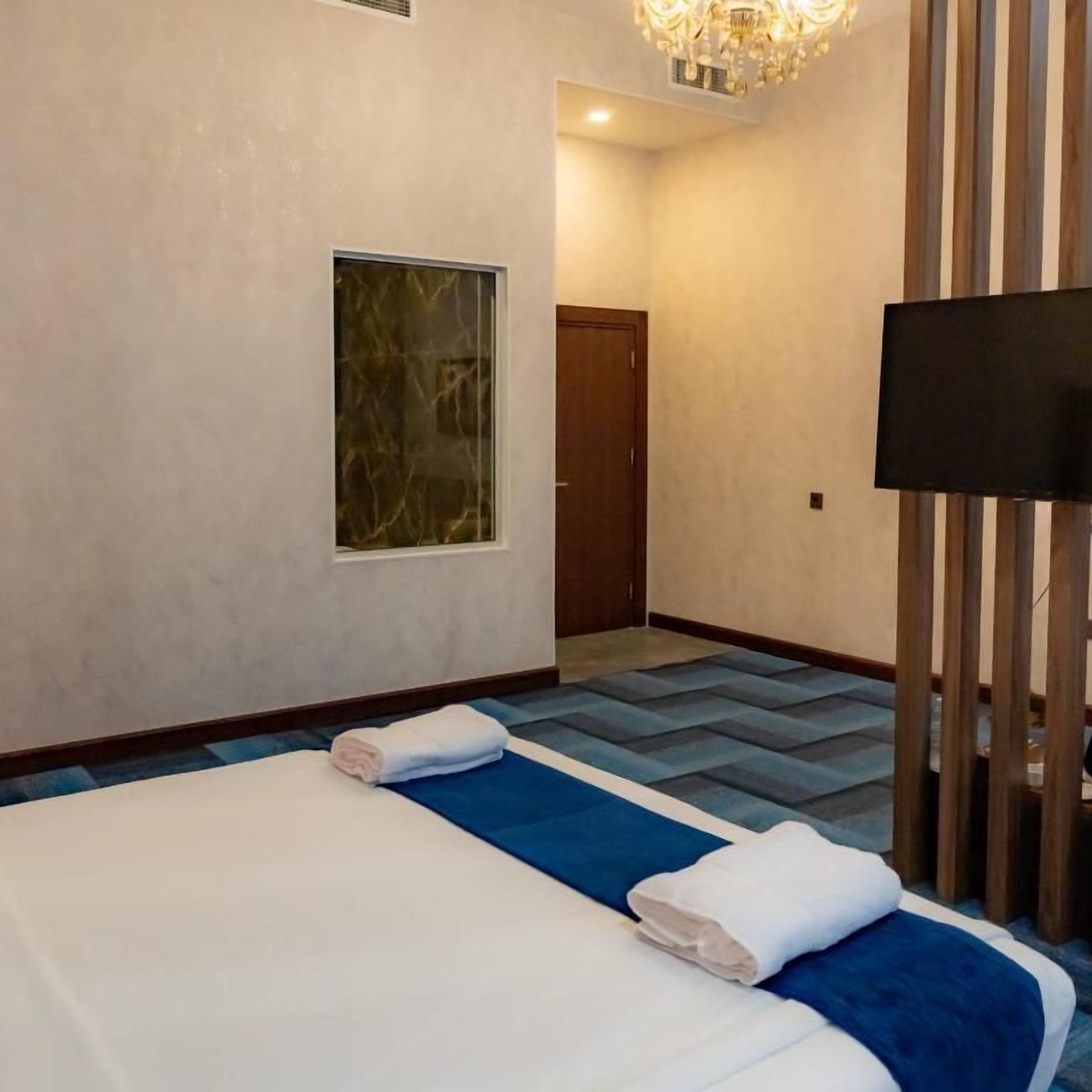A hotel room with a bed, a television, a window, and a door.