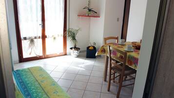 Uma sala de jantar com uma mesa posta para dois, um banco e um vaso com planta.