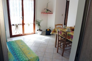 A dining area with a table set for two, a bench, and a potted plant. - Comfy Home Near the Beach (Rosolina)