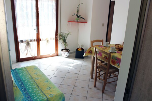 A dining area with a table set for two, a bench, and a potted plant. - Comfy Home Near the Beach (Rosolina)