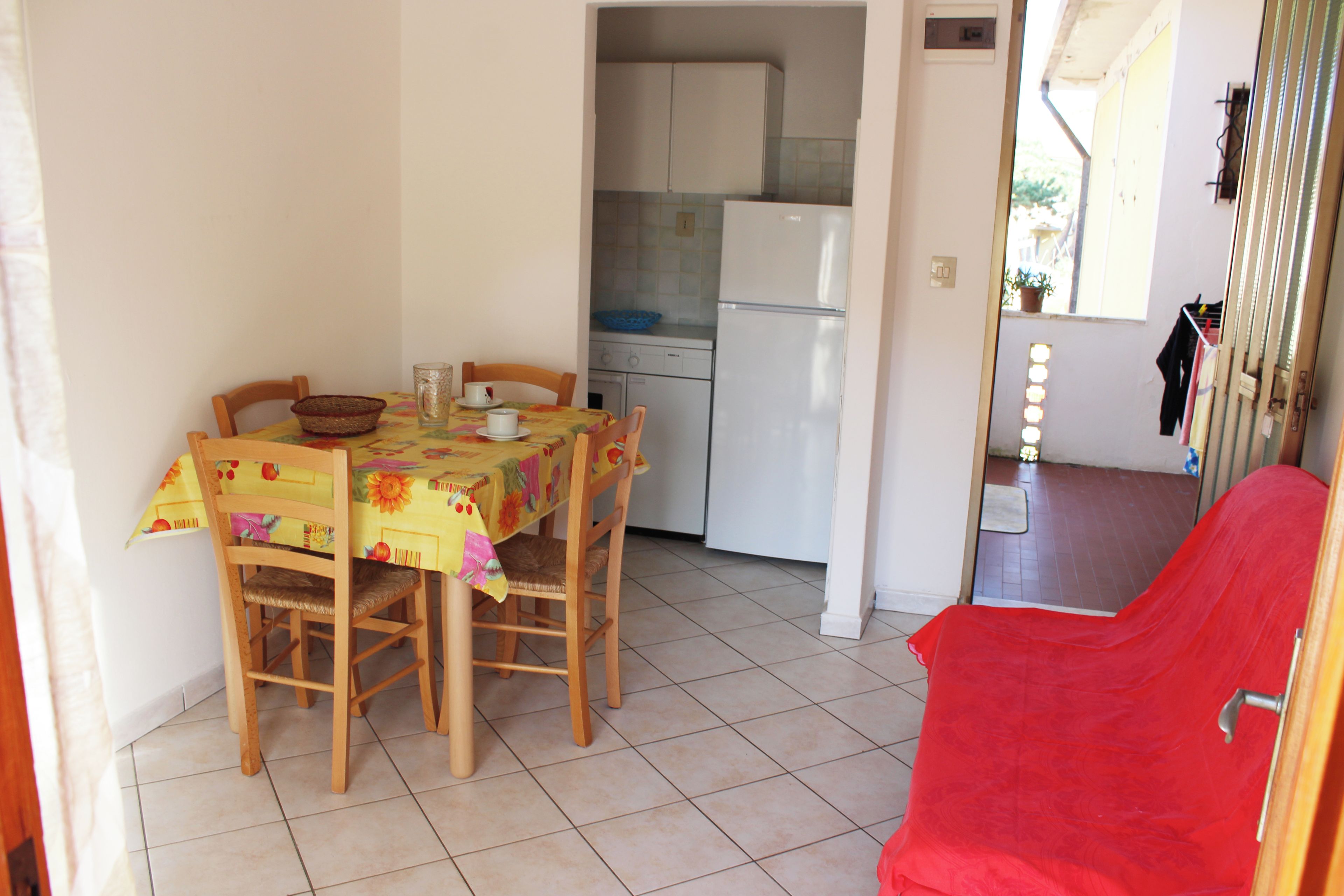Cozinha compacta com mesa de jantar, cadeiras e uma cadeira vermelha.