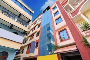 Un edificio de varios pisos con espacios residenciales y comerciales, que cuenta con balcones, ventanas amplias y un cielo despejado.