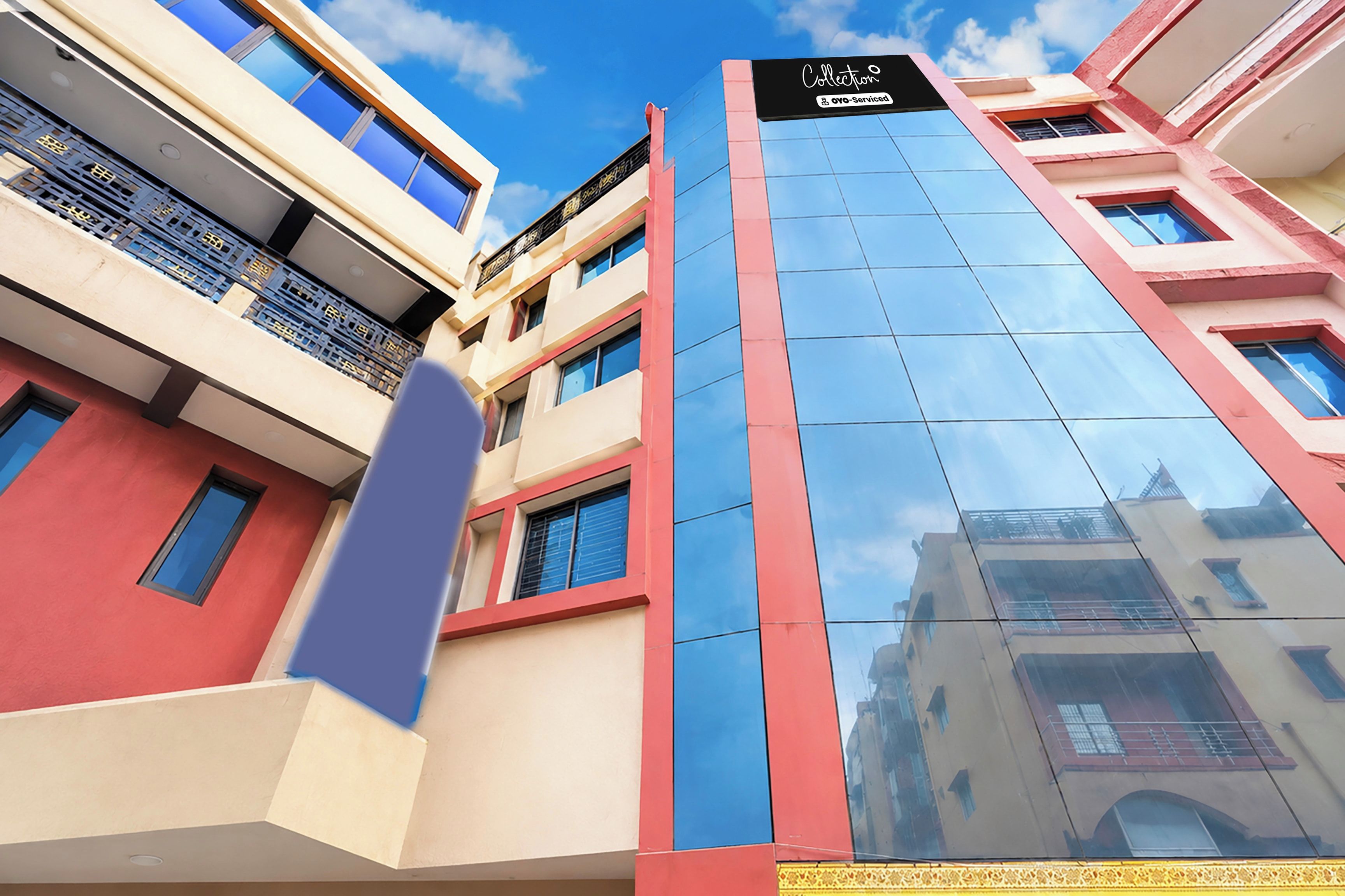 A multi-story building with a reflective glass facade, a prominent sign at the top, and a clear blue sky in the background.