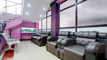 A room with a purple wall, a large window, a television, and a sofa.