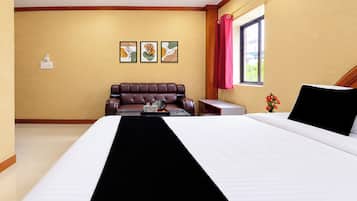 Una habitación de hotel con una cama, un área de estar con una mesa de centro y una ventana con cortinas.