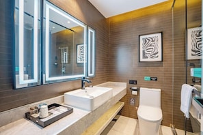 A modern bathroom with a large mirror, a sink, and a toilet. - Pazhou Xana Deluxe International Hotel (Guangzhou)