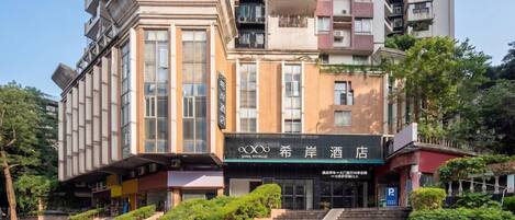Un hotel con fachada moderna, varios balcones y una escalera que conduce a la entrada.