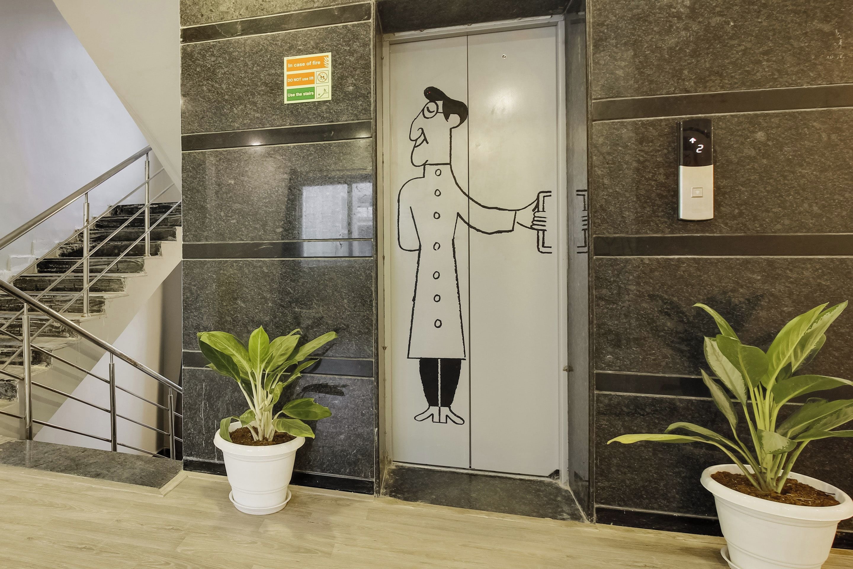 Entrada de hotel con una puerta, una escalera y dos plantas en macetas.
