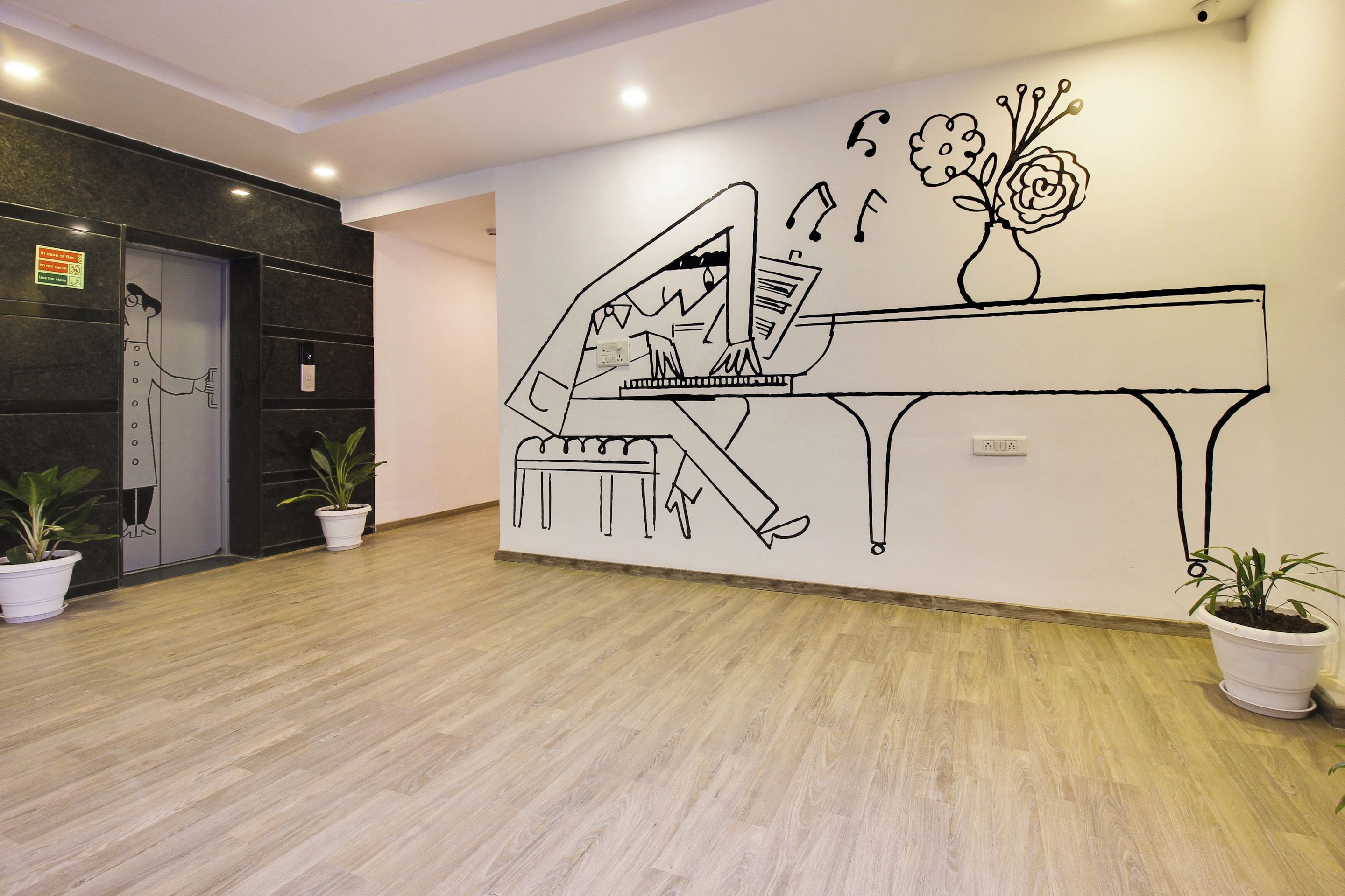 Un hall d’entrée agrémenté d’une fresque représentant un piano, de plantes en pot et d’un comptoir d’accueil.