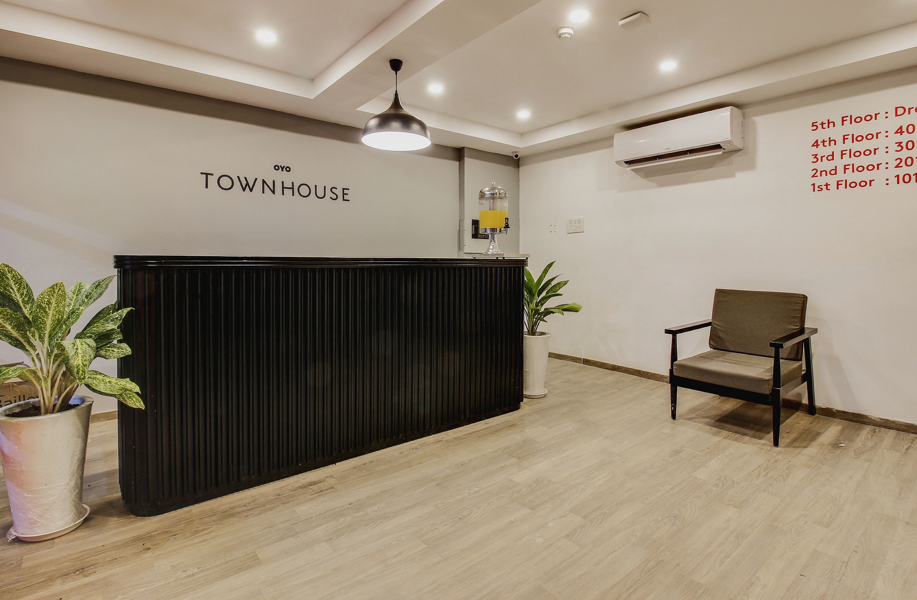 Bancada de recepção com uma placa indicando 'TOWNHOUSE' e um quadro com a lista de números de andares e contagem de quartos.