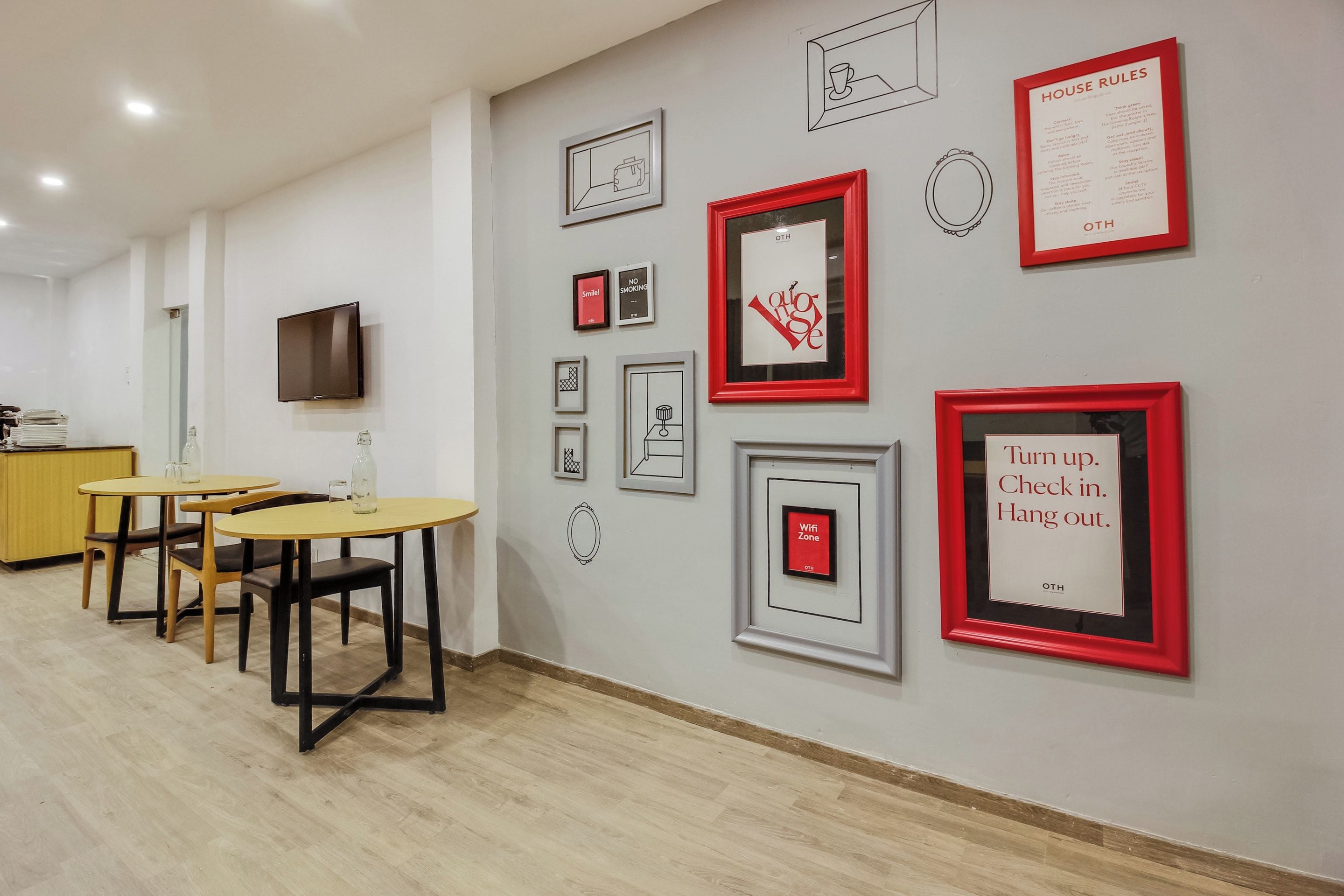 Un hall de hotel con mostrador de recepción, zona de estar y una obra de arte en la pared.