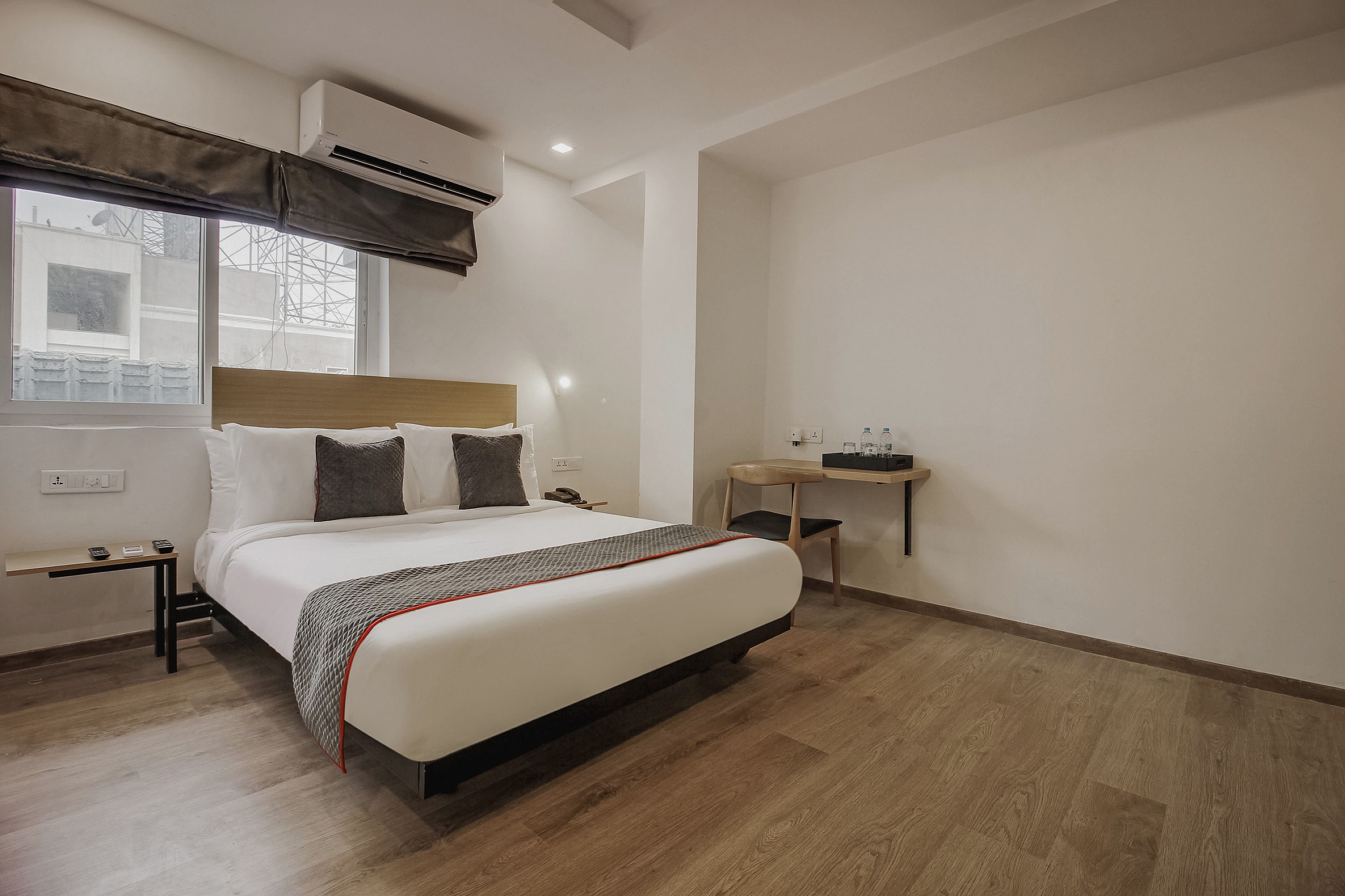 Una habitación de hotel con cama, mesita de noche y un pequeño escritorio con silla.