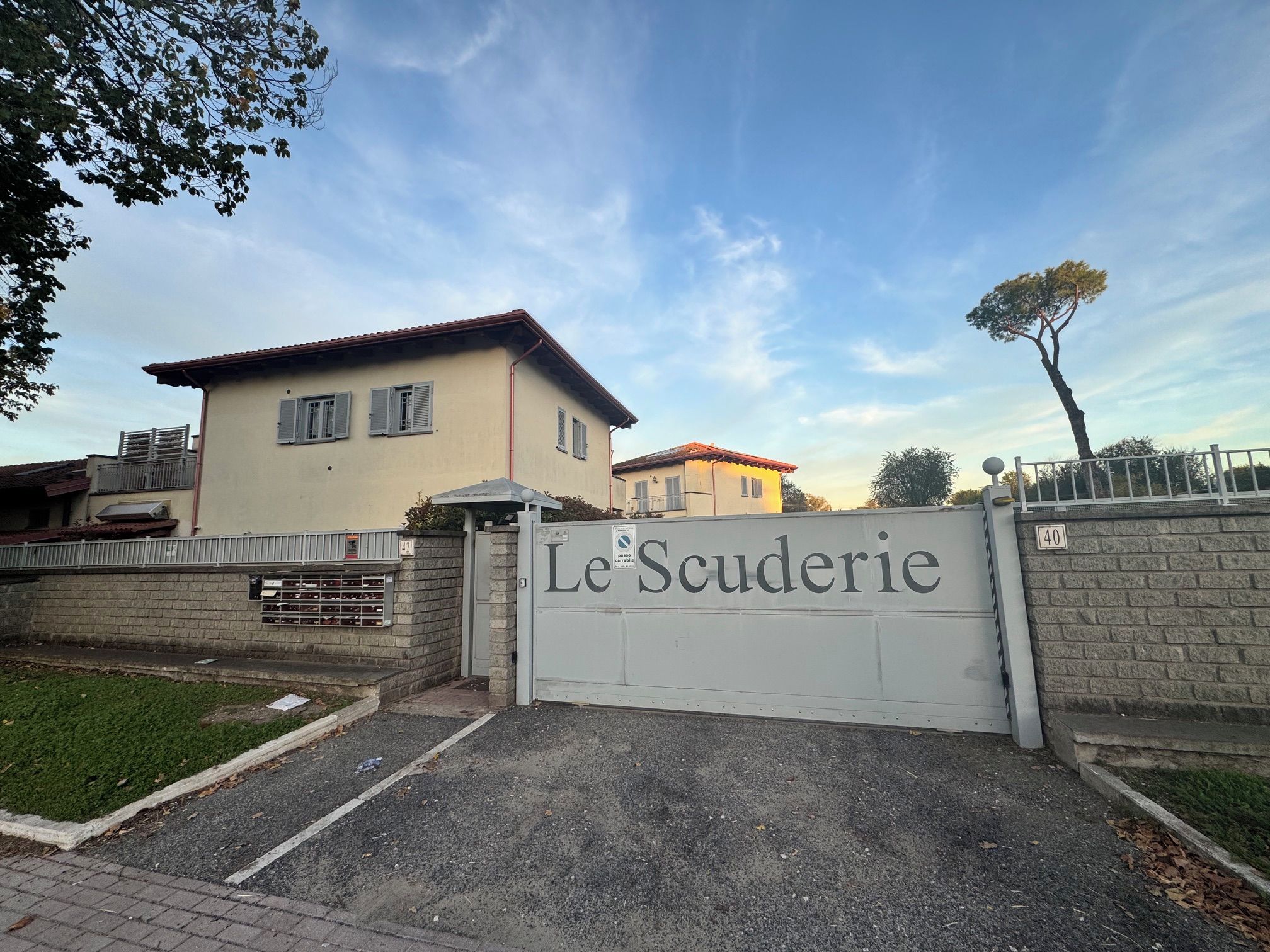 A gated entrance with a sign reading 'Le Scuderie.'