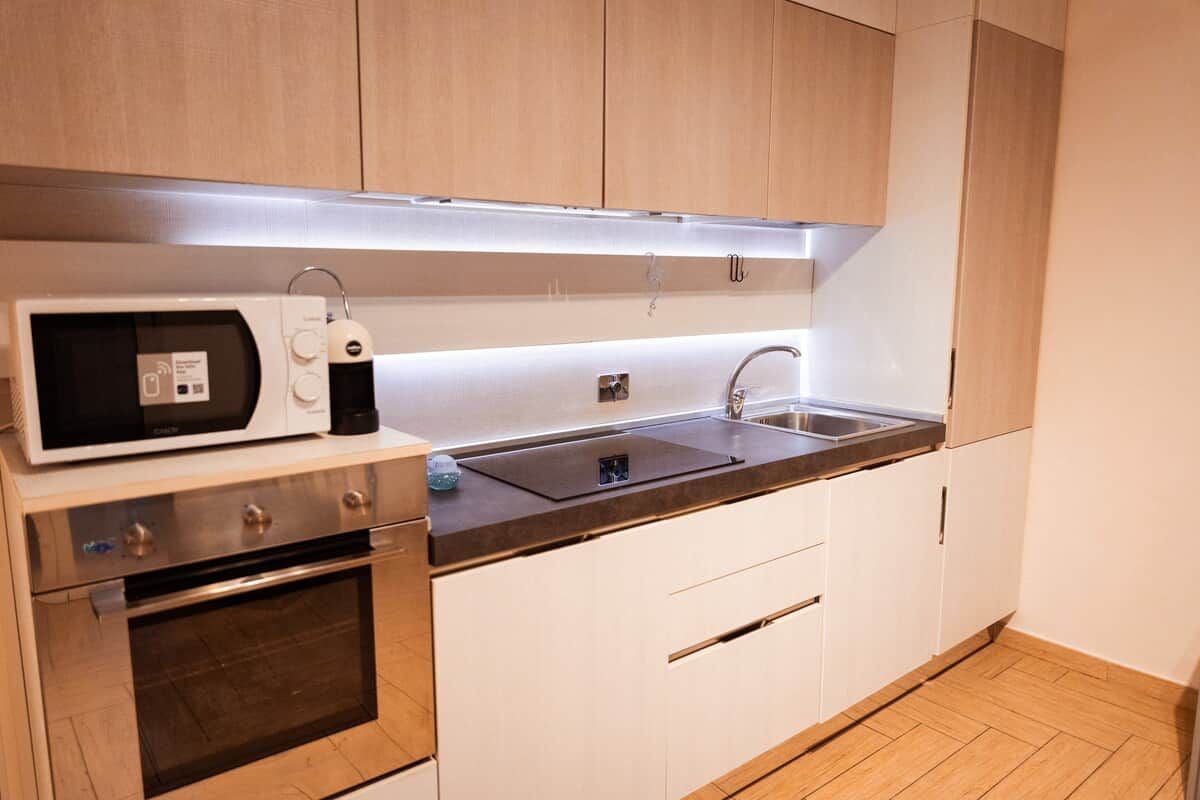Eine moderne Küche mit Mikrowelle, Backofen, Spüle und Holzschränken.