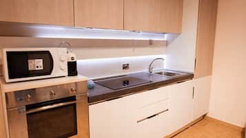 Eine moderne Küche mit Mikrowelle, Backofen, Spüle und Holzschränken.