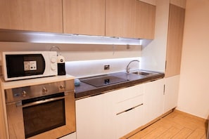 A modern kitchen with a microwave, oven, sink, and wooden cabinets.