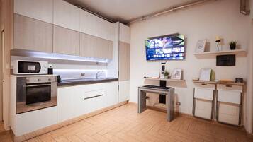 A modern kitchen with a built-in oven, microwave, and a flat-screen TV mounted on the wall.