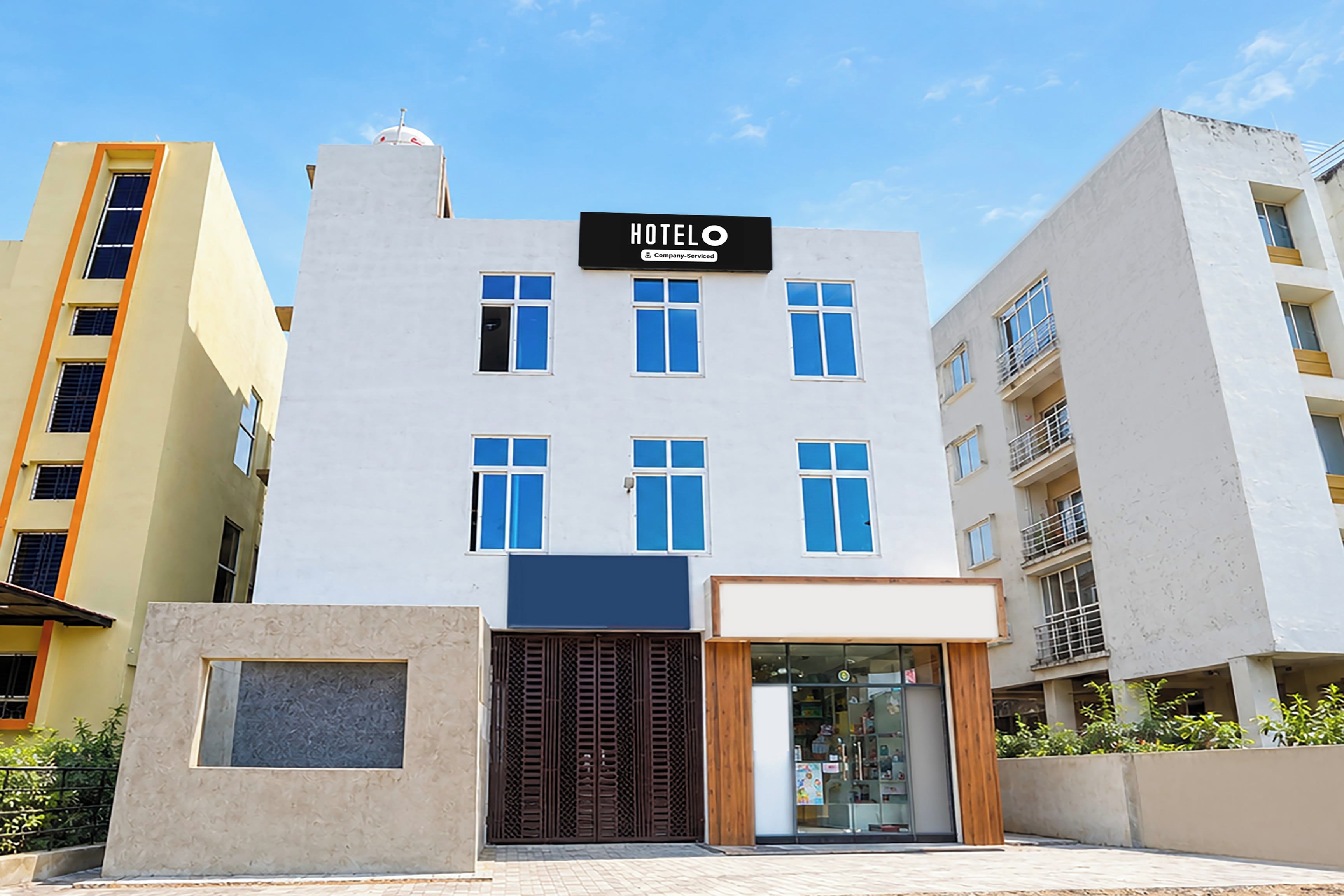 Un hotel con letrero, varias ventanas y entrada protegida por una reja.
