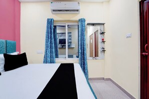 Ein Hotelzimmer mit Bett, einem Fenster mit Vorhängen, einer Klimaanlage und einer Tür.