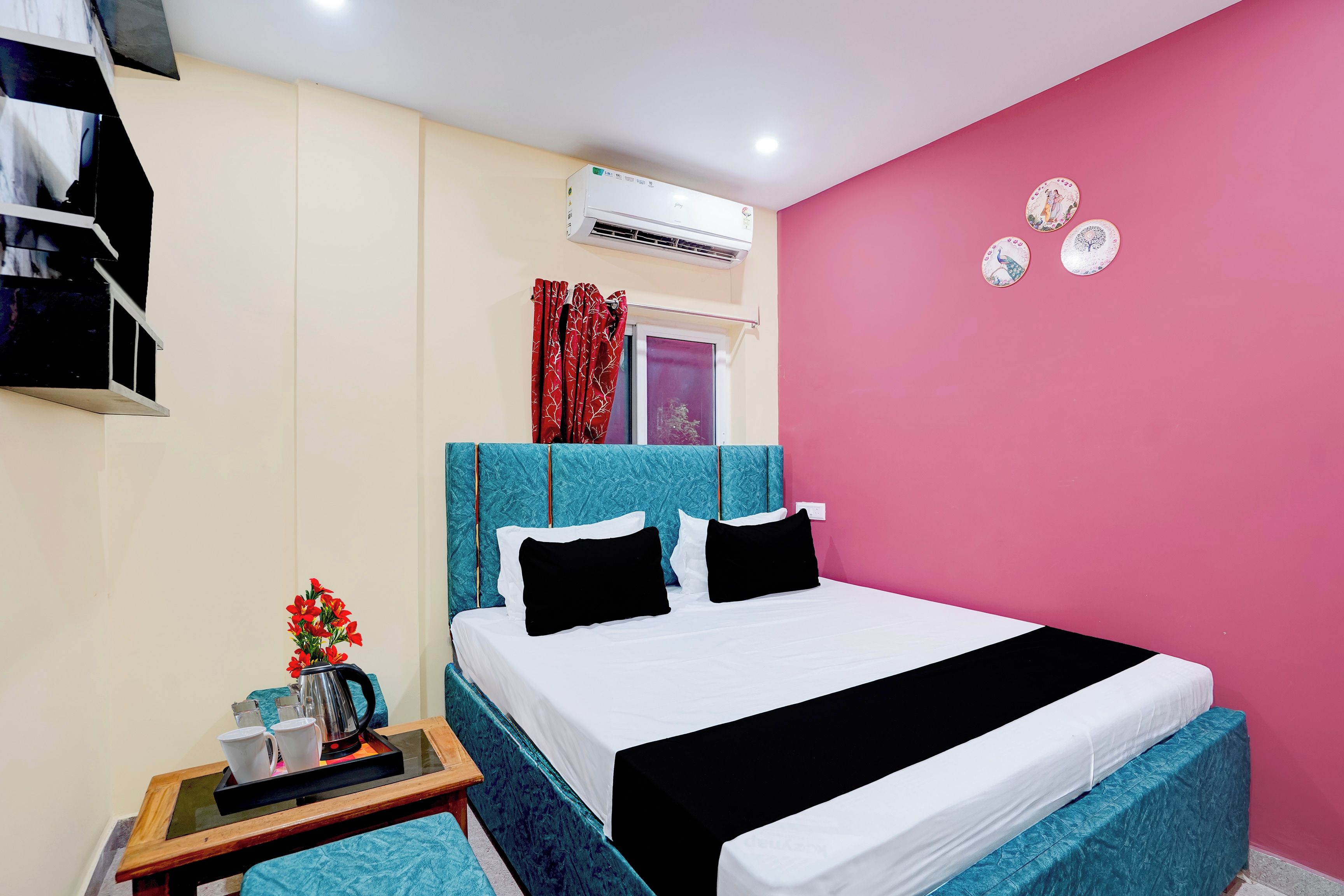 Un dormitorio con cama, mesita de noche, cafetera y platos decorativos en la pared.