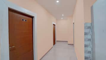 Un pasillo con puertas de madera, suelo de baldosas y pared de color claro.