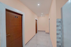 Un pasillo con puertas de madera, suelo de baldosas y pared de color claro.